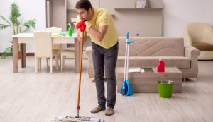 Uomo che fa le pulizie di casa controvoglia